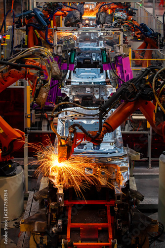 Robotic arms are welding body weld points on an automated production line at an automobile factory.