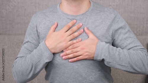 Adult holding the chest due to discomfort, chest pain, or possible heart-related symptoms. Concept of cardiovascular health, heart attack warning signs, medical emergency, healthcare.
