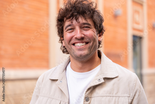 Tableau sur toile Smiling broadly, a happy man with curly hair and a nose ring exudes joy and a fr