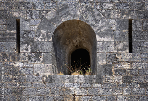 Foto ancient stone fortress wall with an arched embrasure window and vertical arrow s