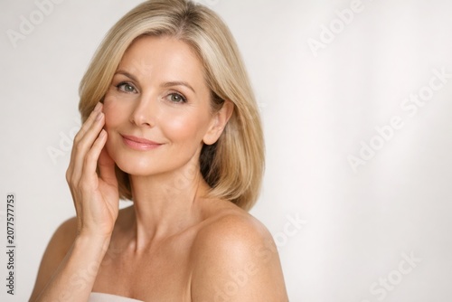 Beautiful mature woman with healthy glowing skin smiling softly in elegant natural beauty portrait