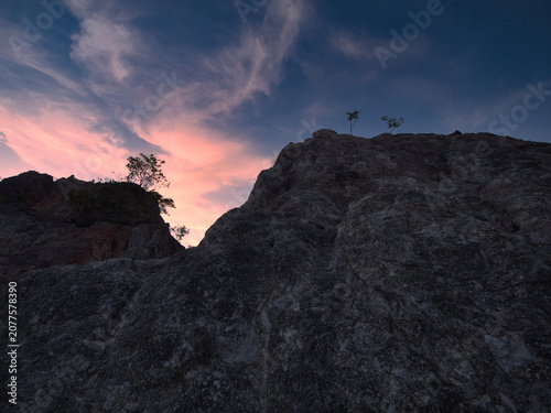 Konstfotografi Limestone mountains at dawn, featuring a sharp and unique landscape with sparse vegetation set against a backdrop of sky and clouds in Surat Thani Province, Thailand