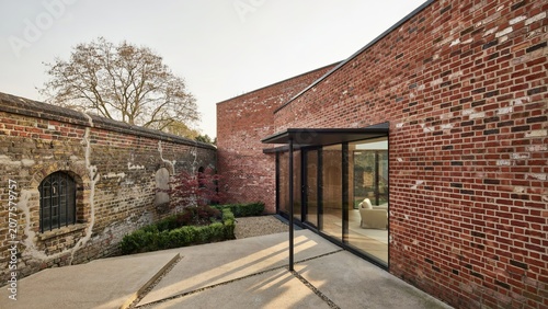 Brick building features a modern glass extension that blends rustic historical walls with contemporary home design.