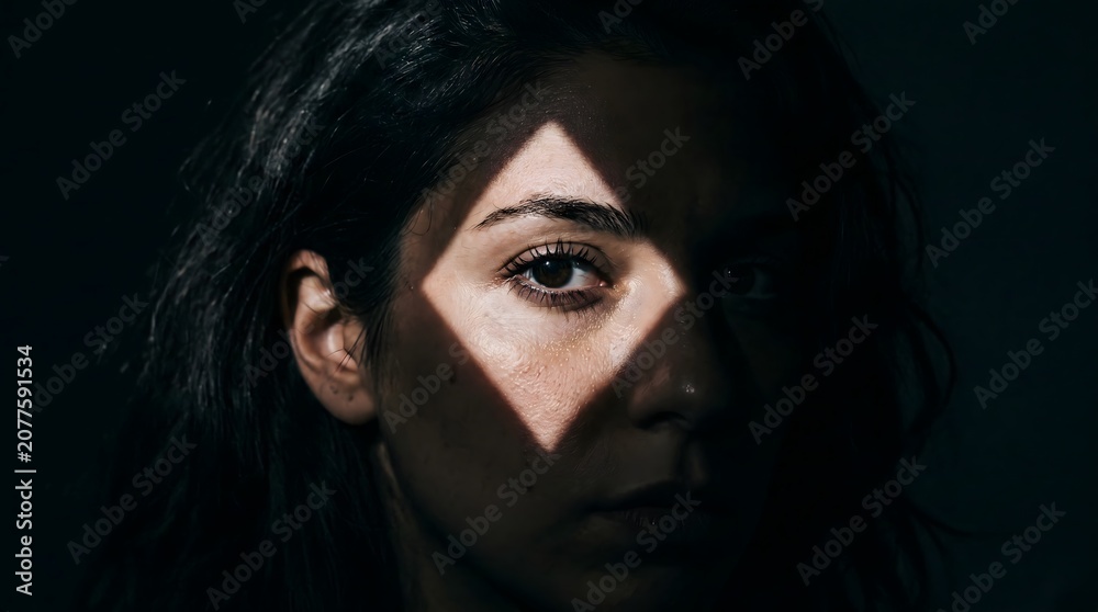 Fototapeta premium Dramatic shadow woman face with diamond shaped light on eye