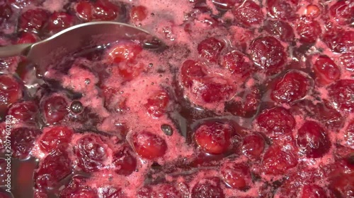 Cooking cherry jam while stirring with a spoon in boiling syrup in close up