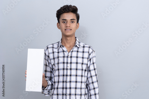 Foto Portrait of an indian young boy showing and holding aadhar card on white