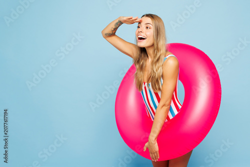 Young happy sexy woman wear bikini swimsuit sunglasses rest near hotel pool hold pink rubber ring look far away aside on area isolated on plain blue background. Summer vacation sea sun tan concept