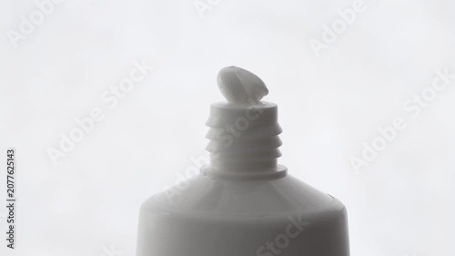 Hand cream in a tube, white texture leaking onto the packaging, front view.