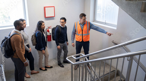 Floor warden guiding orderly stairwell evacuation drill in office building