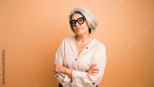 Фотография Elegant senior woman with glasses and grey hair posing confidently, looking at t