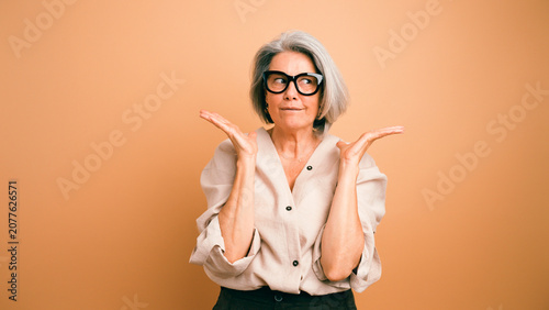 Foto Senior woman in eyeglasses shrugging, looking to the side with a puzzled facial