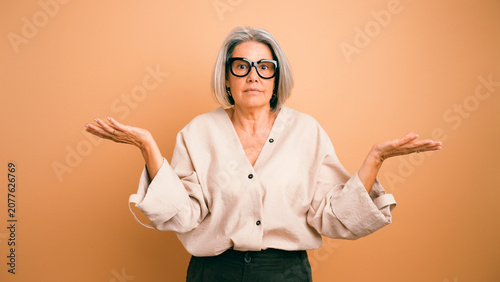 Quadro su tela Senior woman with gray hair and glasses shrugging, expressing uncertainty, doubt