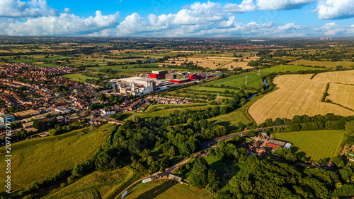 Wide high angle view of industrial factory complex near residential town and green fields
