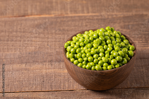 Fresh green peas and pods in a bowl on wooden table. Vegetable healthy food.  