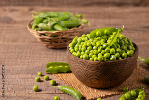 Fresh green peas and pods in a bowl on wooden table. Vegetable healthy food.  