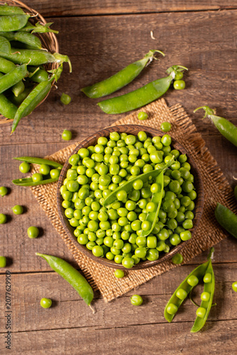 Fresh green peas and pods in a bowl on wooden table. Vegetable healthy food.  
