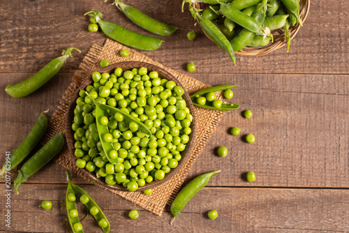 Fresh green peas and pods in a bowl on wooden table. Vegetable healthy food.  