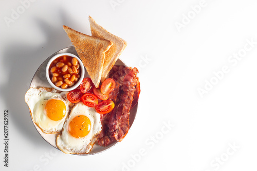 Delicious traditional English breakfast with fried eggs, beans, bacon, tomatoes and toasts