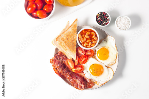 Delicious traditional English breakfast with fried eggs, beans, bacon, tomatoes and toasts