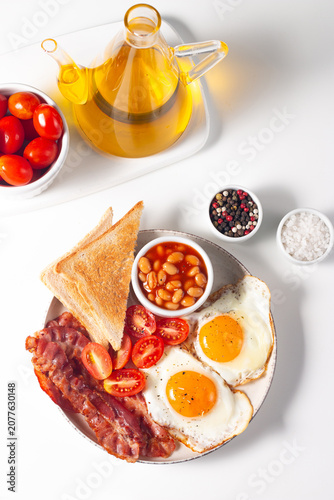 Delicious traditional English breakfast with fried eggs, beans, bacon, tomatoes and toasts