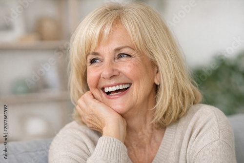 Joyful older woman smiling and posing indoors.