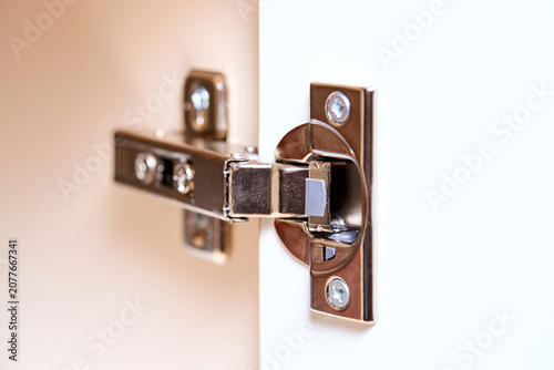 Fotografie Furniture hinge with door closer made of metal on white cabinet door for smooth opening and closing