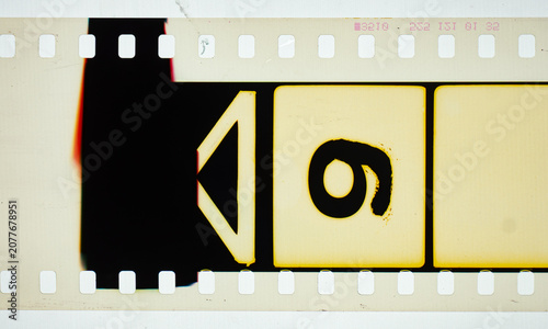 Vintage 35mm motion picture film countdown leader strip featuring the number 9 and a directional arrow. Authentic analog cinema celluloid frame macro isolated on a bright white background