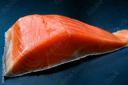 close up of a raw salmon fillet on a black background
