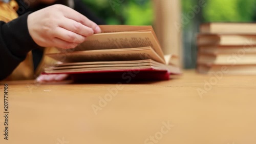 Young woman reading open book on desk. Student enjoying education and literature study. Academic learning process at home or library. Knowledge development, research and hobby concept.