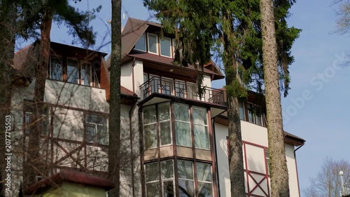 Residential building with timber framing architecture. Modern hotel or townhouse surrounded by forest trees. Exterior view of luxury mountain resort cottage for travel destination.
