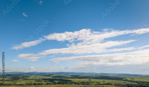 Polish beautiful landscape of late spring, featuring green hills, fields, and forests, with the Sudety Mountains in the background near Polanica-Zdroj