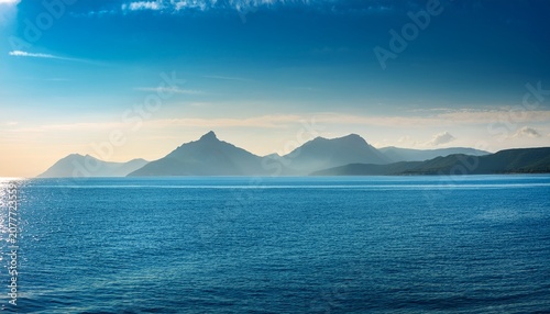 Sunlit Calm Sea With Distant Mountains