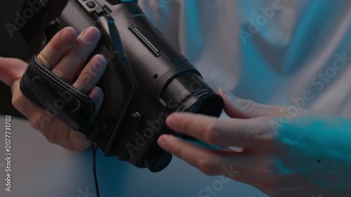 Cameraman hands holding and operating vintage analog video camera woman hands help with final settings. Concept of moment of teamwork in retro inspired film production scene, close-up, slow motion