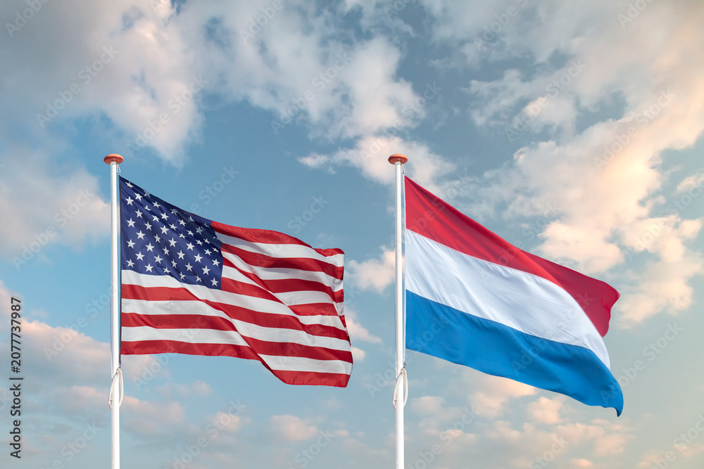 Obraz premium Waving American and Dutch flag in front of a blue sky