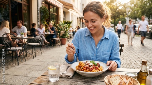 Smiling woman serving homemade pizza outdoors in cafe.