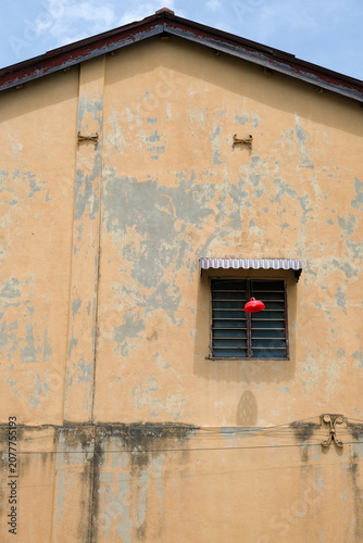 Weathered yellow heritage wall with red industrial lamp in George Town Penang