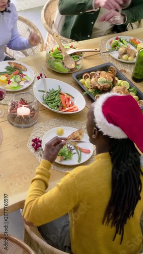 Vertical video: Serving lady in yellow jumper and Santa hat at holiday table, roast bird and wine
