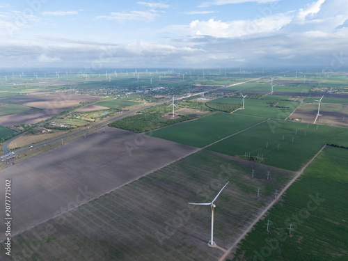 Фотография Wind turbines stand tall in neat rows against a vast agricultural landscape, rot