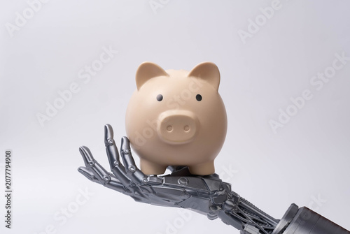 Futuristic robotic hand holding piggy bank, symbolizing artificial intelligence in finance, smart savings, digital banking, investment technology, and automated money management solutions.