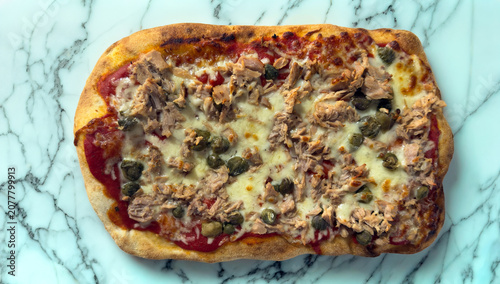 Roman pinsa with tuna mozzarella and capers on white marble background