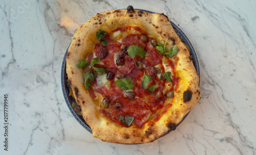 Authentic Neapolitan pizza with salami olives and fresh basil