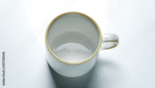 A close-up shot of an empty white mug with gold trim on a plain surface