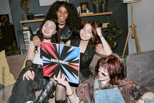 Multiethnic teens gathering, holding rock music vinyl record, smiling on sofa and celebrating friendship, youth culture, entertainment. Ideal for lifestyle, music marketing, social campaigns