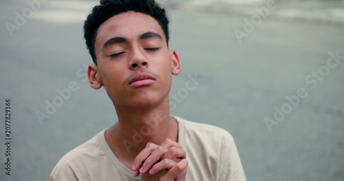 Photography Teenage boy with a peaceful expression, eyes closed, hands clasped in a prayerfu