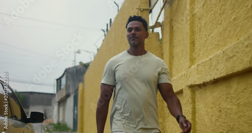 Foto Hispanic Afro-Latin man walking forward along yellow wall, confident and relaxed