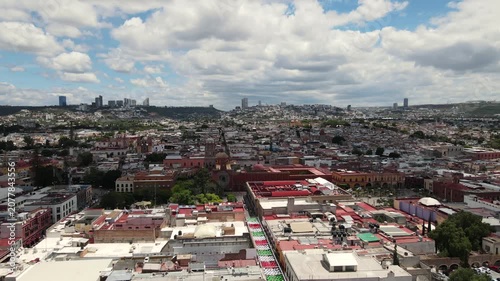 An aerial drone footage featuring an upward movement and panoramic view of Queretaro City, Mexico. The shot showcases the contrast between the classic colonial architecture of the historic downtown in