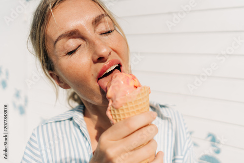 A close-up an unrecognizable woman holding a melting ice cream in a waffle cone.