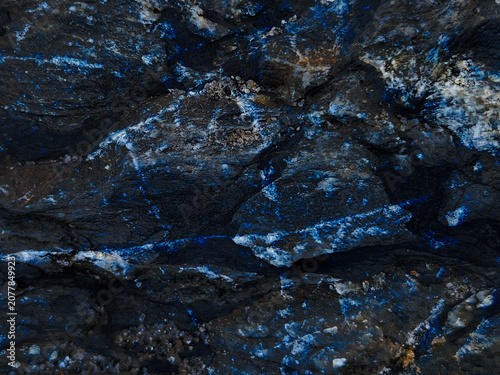 Vibrant blue mineral veins in dark stone surface adorned with white speckles, background, texture