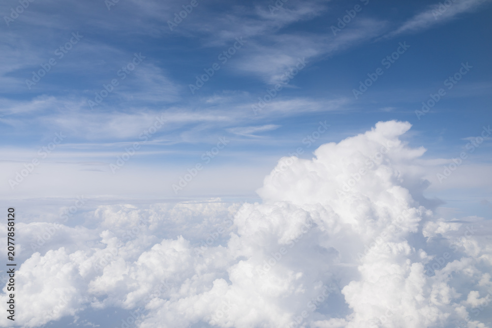 Fototapeta premium Beautiful aerial view of fluffy white clouds against a vibrant blue sky from an airplane window.