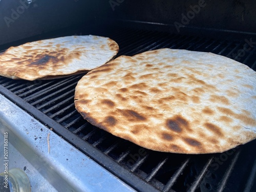 Frisch gegrilltes Fladenbrot auf dem Grillrost. Authentisches BBQ-Motiv zu Outdoor Cooking, Grillen, mediterraner Küche, Pizza, Flammkuchen und hausgemachtem Genuss.